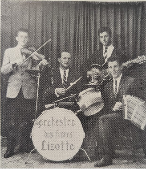 Black and white photograph of the Orchestre des Frères Lizotte. From left to right, all wearing jackets and ties: Jean-Paul Lizotte, Jean-Léon Pelletier, Maurice Lizotte and Réjean Lizotte. Some band members are sitting and others are standing in front of a curtain.