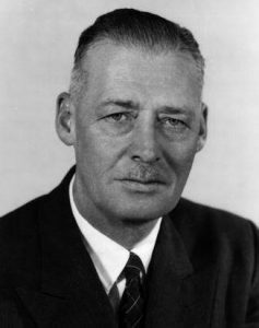 Black and white portrait photograph of an older man wearing a jacket and tie