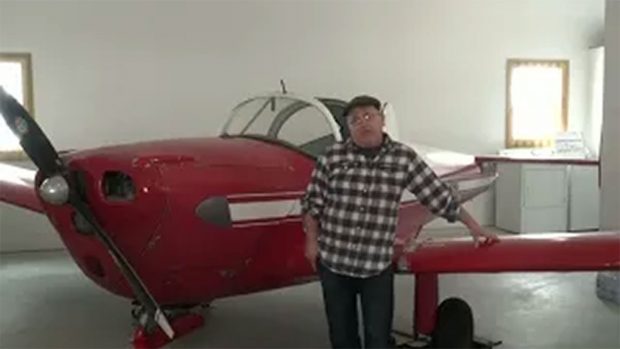 A coloured photo of Bryan Hood stood in front of a vintage airplane being interviewed.