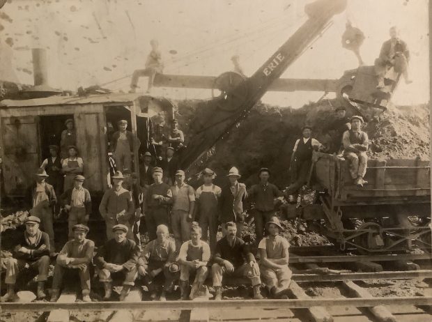 A black and white photograph of 30 quarry workers- the men stand beside a steam shovel.