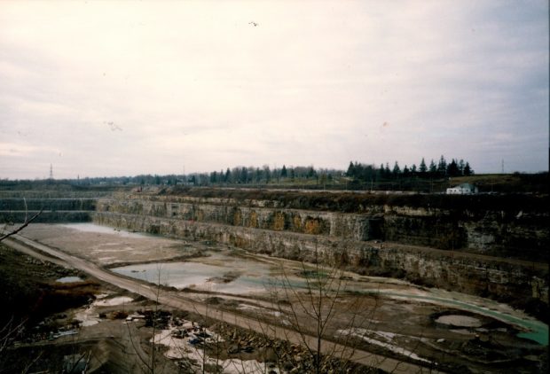 A colour photograph of a quarry pit with three tiers of rock faces