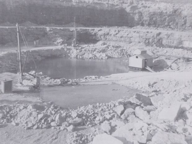 A black-and-white photograph of a pump house on the floor of a quarry pit