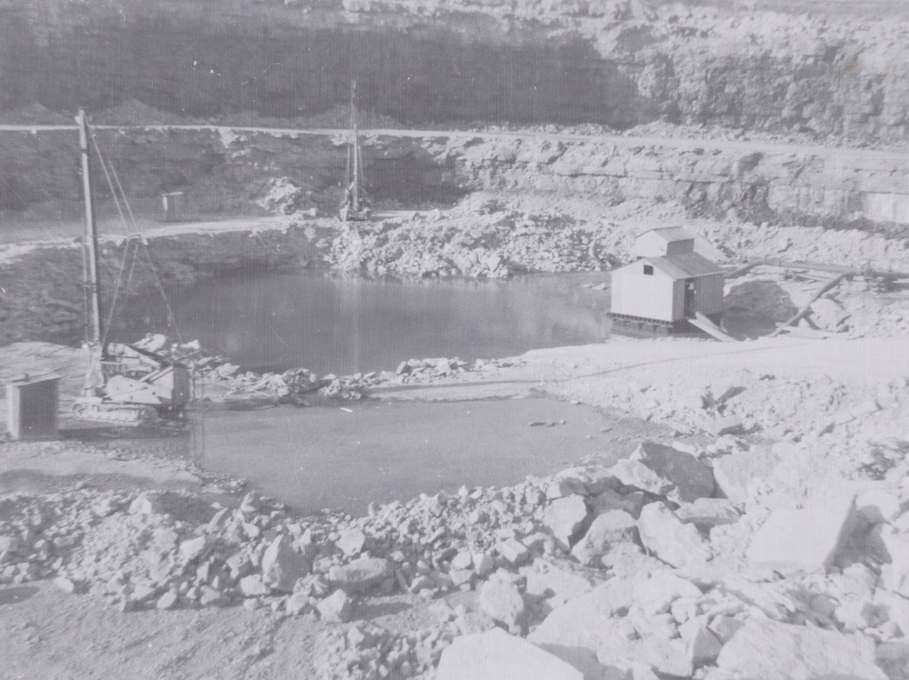 A black-and-white photograph of a pump house on the floor of a quarry pit