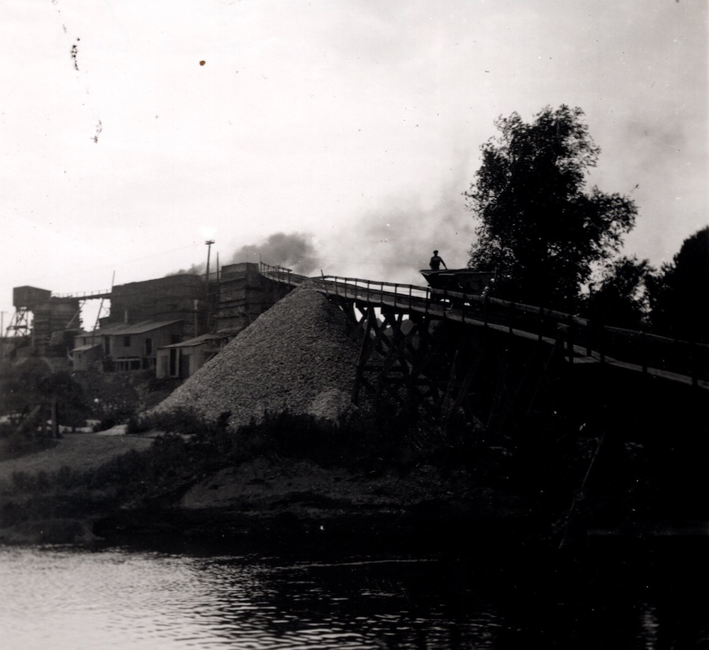 A figure pulls a cart up a wooden ramp, headed to a brick structure.