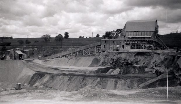 A large industrial building on the edge of a quarry pit