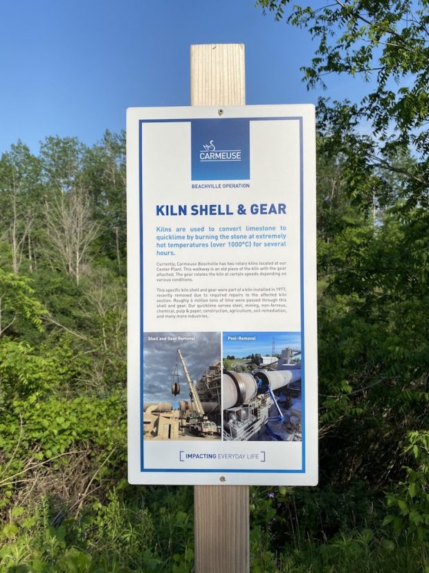 A sign on a wooden post with a blue border, titled Kiln Shell & Gear