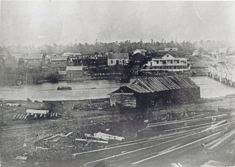 Black and white photograph of a sawmill in Almonte, c. 1850, with the Mississippi River and town of Almonte in the background.