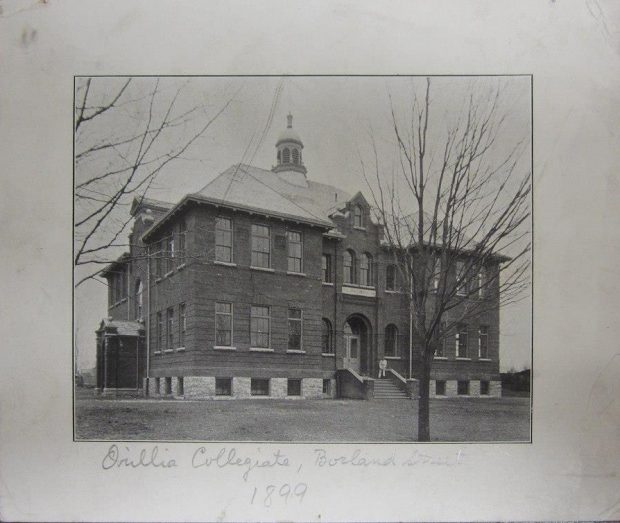 Aged black and white photograph of a man dressed in white sitting at the entrance of a large brick building. Written below the image is Orillia Collegiate, Borland Street, 1899.