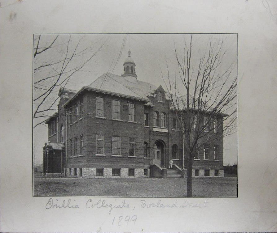 Aged black and white photograph of a man dressed in white sitting at the entrance of a large brick building. Written below the image is "Orillia Collegiate, Borland Street, 1899".