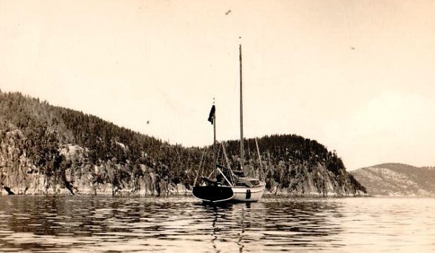 Black and white photograph of a small two-masted sailboat, sails unfurled, moored in a few centimetres of water. The title L'Empress Tadoussac II. Robert Harrington Smith, circa 1950