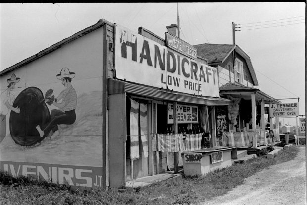 Black-and-white photo of a craft stand attached to a house on the side of Route 138.