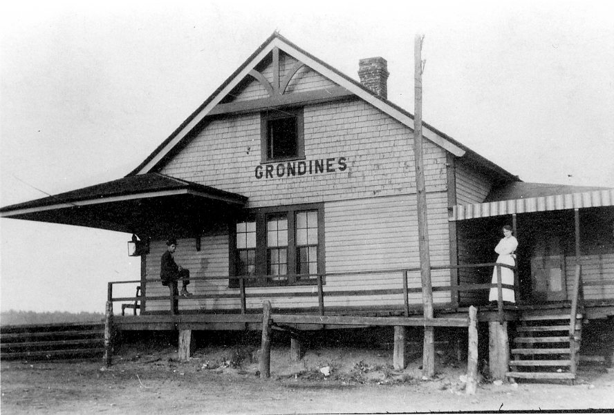 A woman standing and a man seated on the gallery of the Grondines train station.