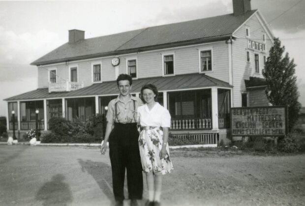 Black and white photo of a couple in front of a hotel.