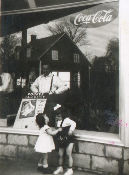 Black and white photo of two small children in front of a window with a man in the background.