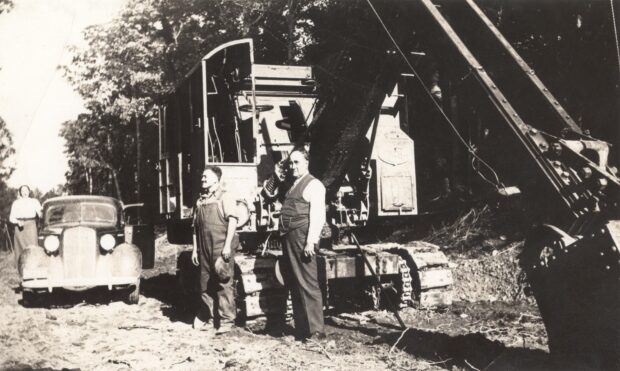 Black and white photo of two men in front of the machinery.