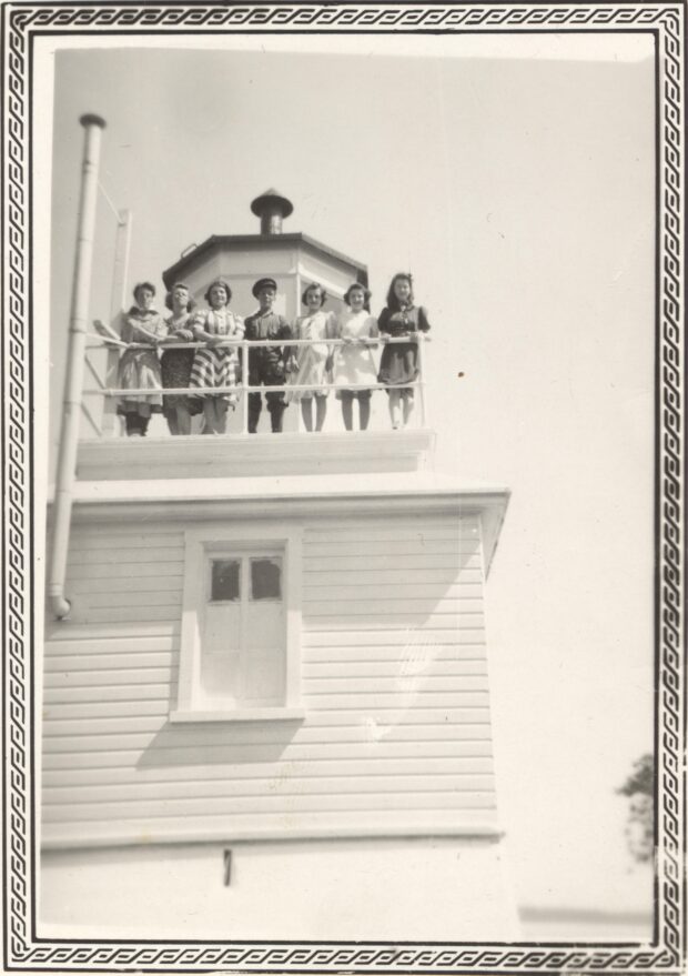 Black and white photo of six young adults at the top of a lighthouse.