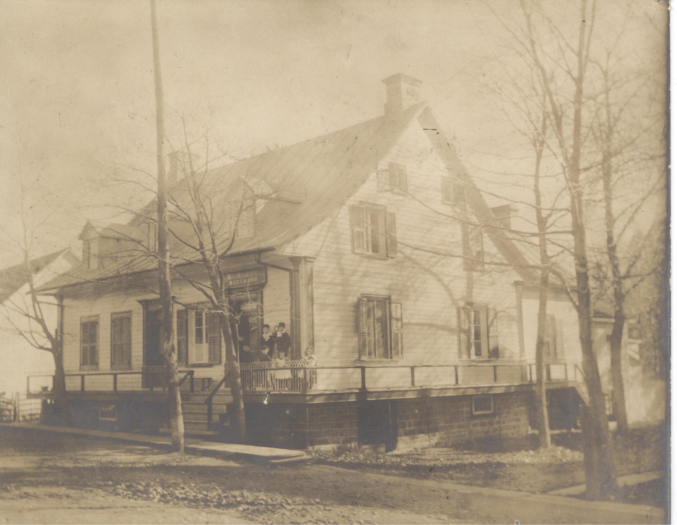 Black and white photo of six children on the porch of a two-storey house.