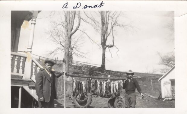 Black and white photo of two men with their fishing catch.