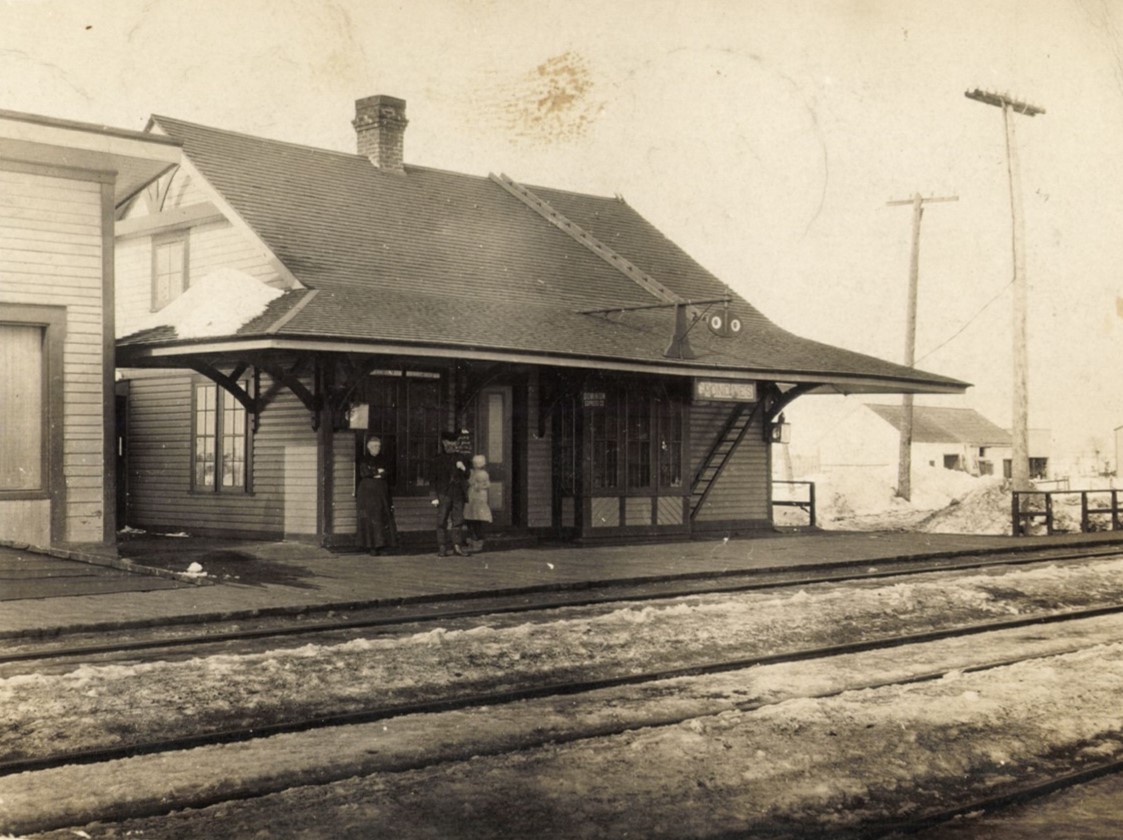 Black and white photo of three people on a train station platform in winter.