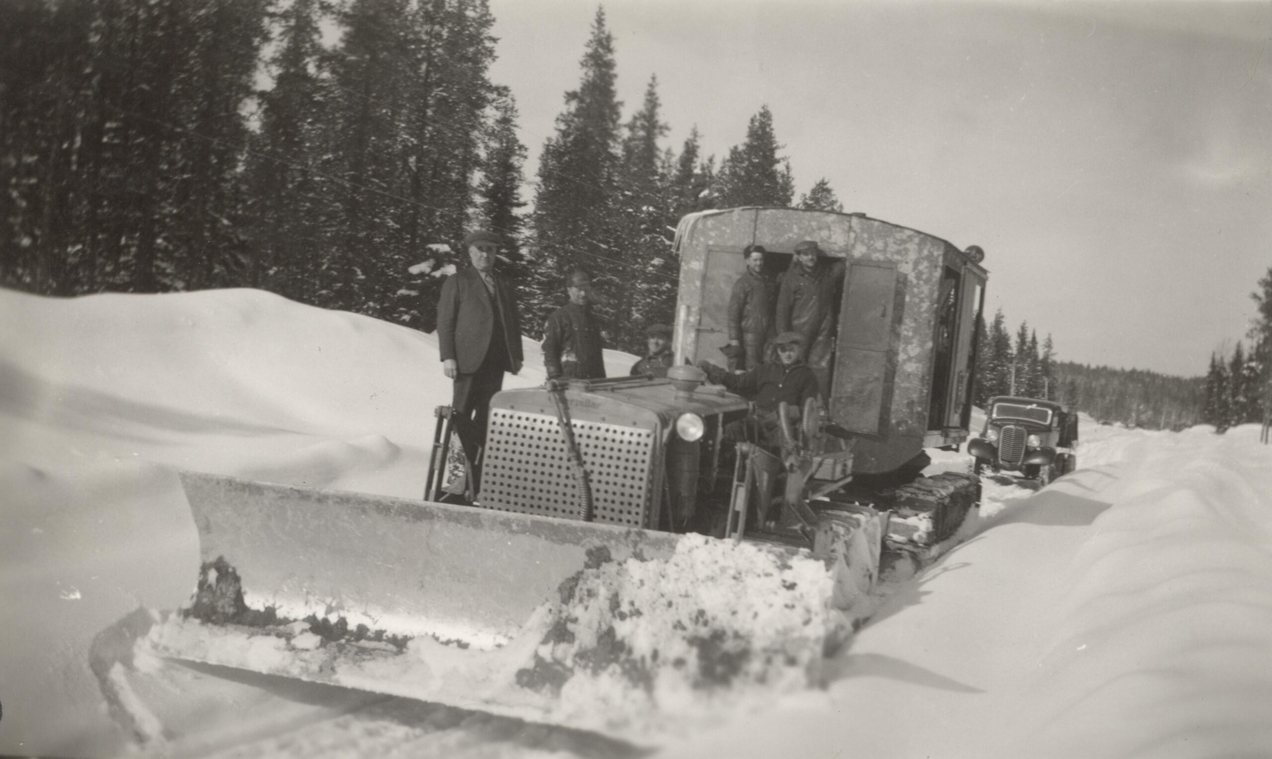 Black and white photo of six men on a snowplow.