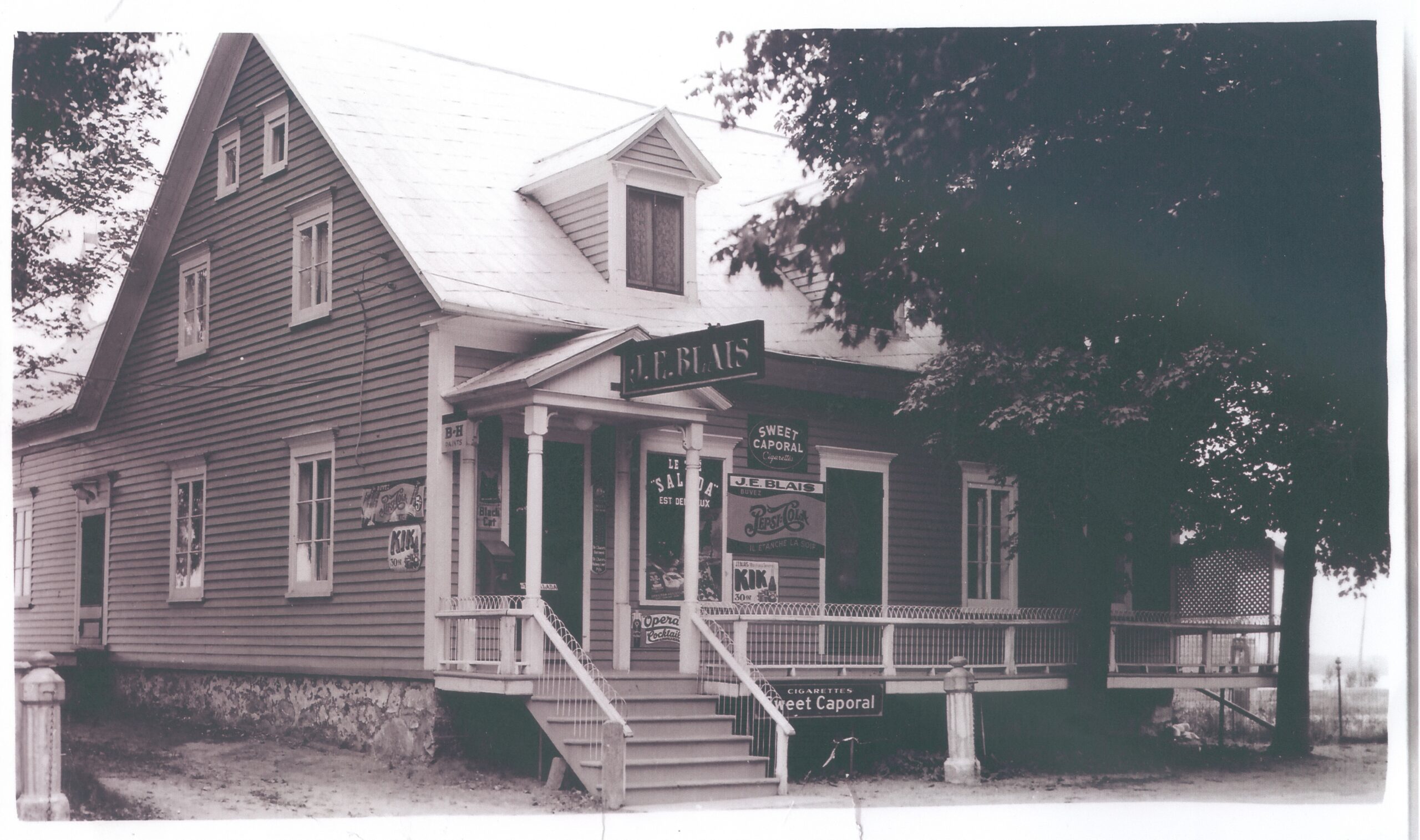 Black and white photo of a two-storey house with a general store on the first floor.