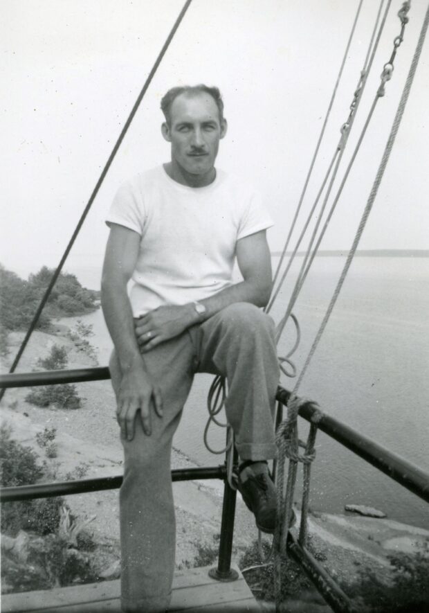 Black and white photo of Ovila Paquet sitting on the railing.