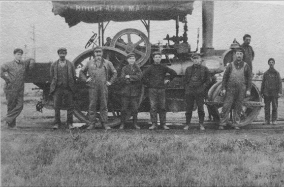 Black and white photo of nine men in front of a roll of tarmac.