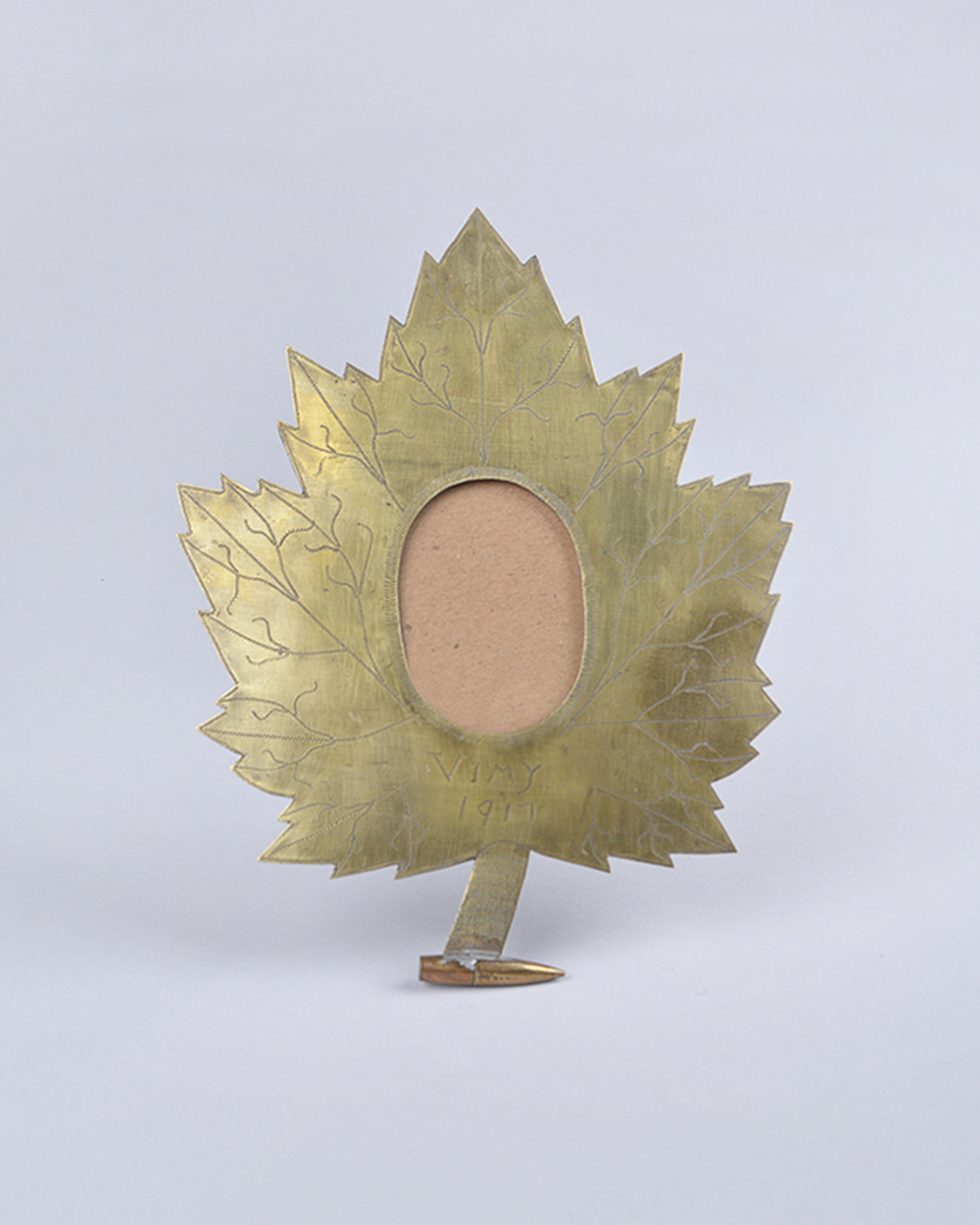 An engraved, maple leaf shaped frame with a circular hole for a picture.