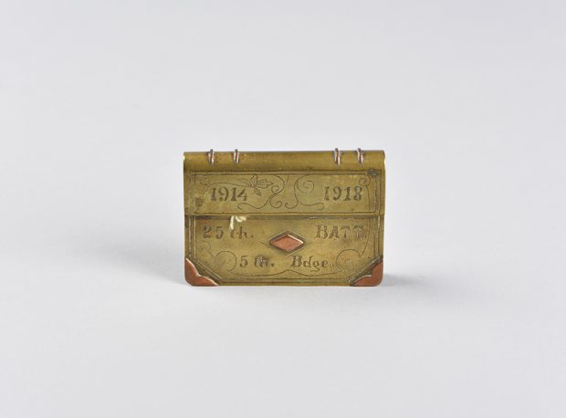 A lighter made from brass and copper, like a satchel and engraved with date and other information.