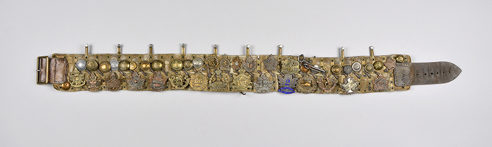 A very ornate belt made from a collection of brass medals and badges.