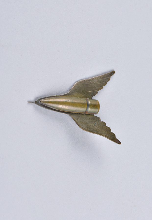 A brass brooch made from a bullet with formed wing shapes.