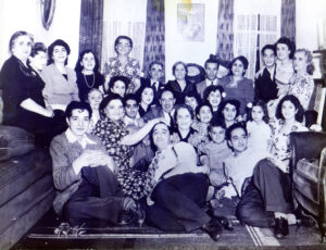 Black and white portrait. Group of 29 people, 8 men, 19 women, one boy, and one girl. Group sitting together in a living room wearing semi formal clothing.