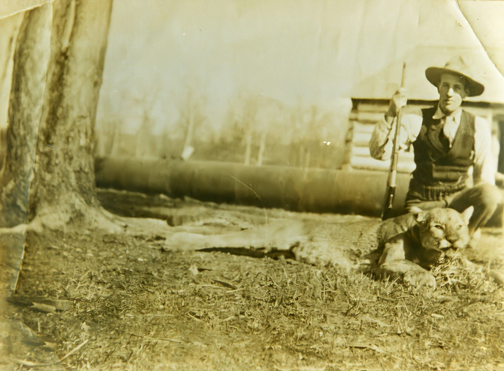 Man with rifle and dead cougar