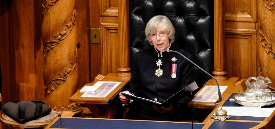 Woman in uniform seated on throne reading document