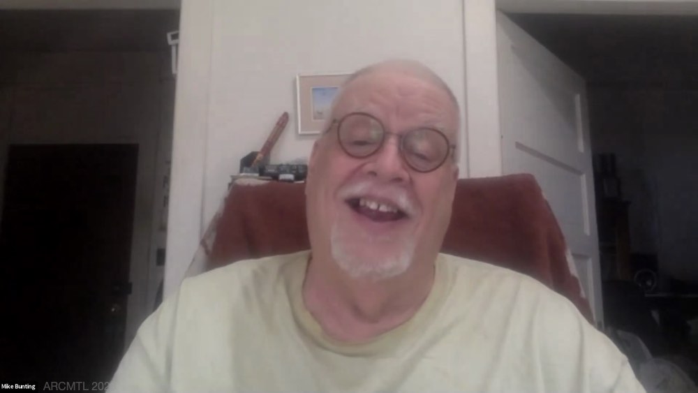 A screenshot from a video chat showing a smiling Mike Bunting sitting in a chair in a room.