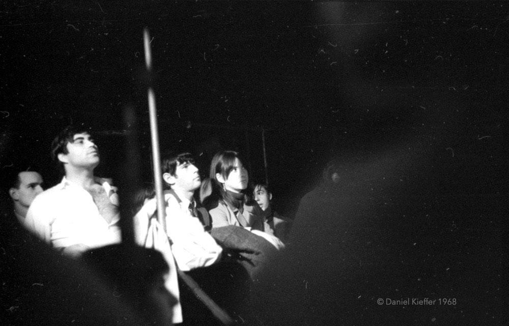 Des jeunes hommes et des jeunes femmes sont assis sur des bancs sur cette photo en noir et blanc prise au New Penelope