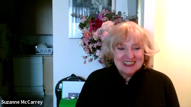 Blonde-haired Suzanne McCarrey is smiling widely and wears a black blouse in a screenshot from a video chat.