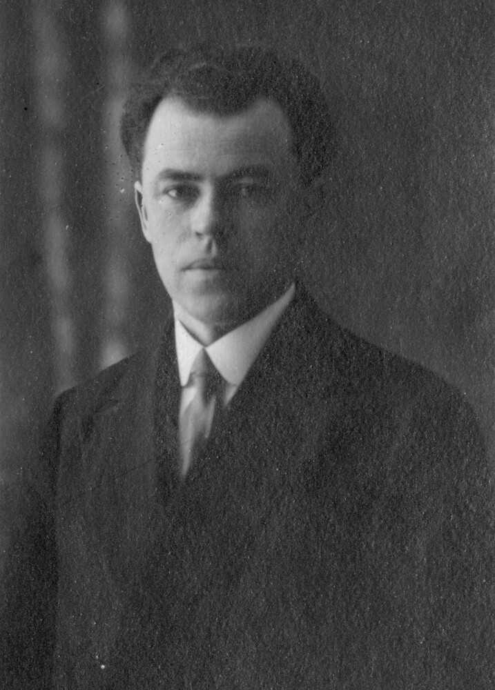 Black and white photograph of a serious-looking man dressed in a suit, facing the camera.