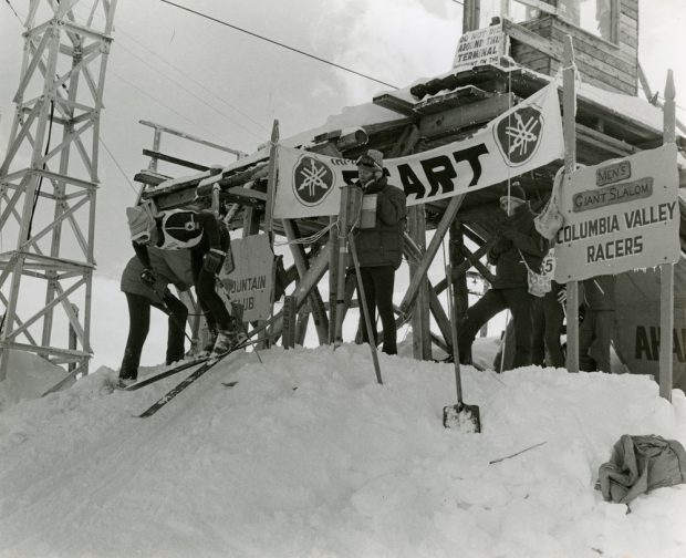 Black and white photograph of a skier pushing off from a starting gate.