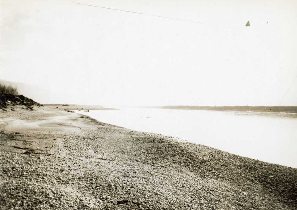 A sepia-toned landscape photograph of a body of water bordered by patches of land.