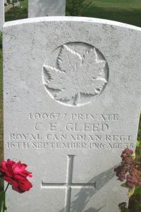 A grave stone with a cross and a maple leaf.