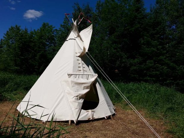 Photograph of a tipi tent outside.