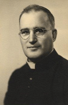 Black and white picture : official portrait of a man in clergyman clothing, wearing glasses.