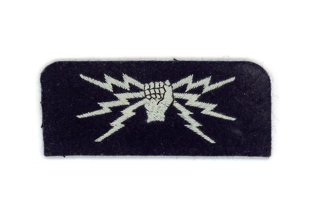 A dark blue felt patch with embroidered white fist holding 3 lightning bolts